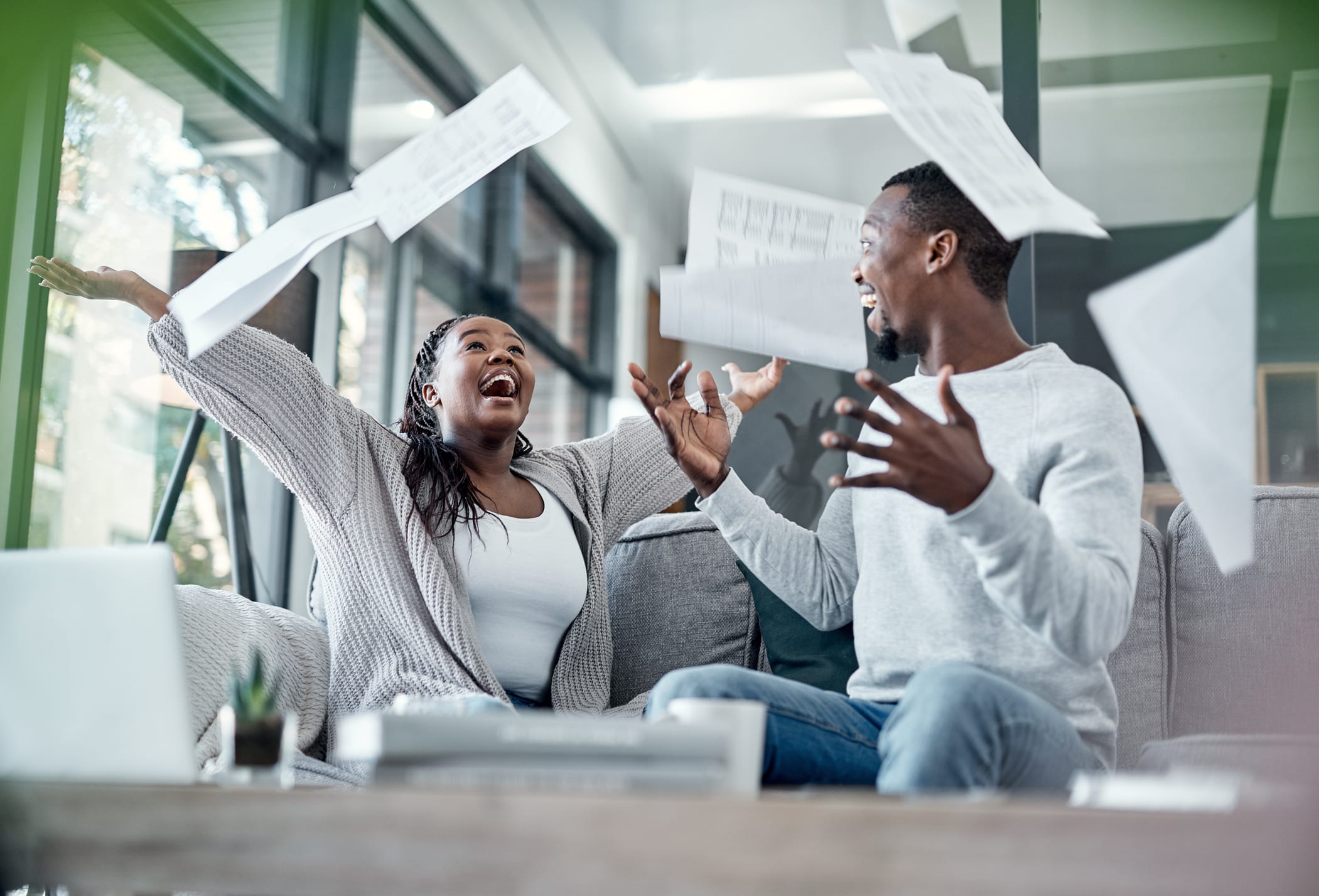 Shot of a young couple celebrating while going through financial paperwork at home.